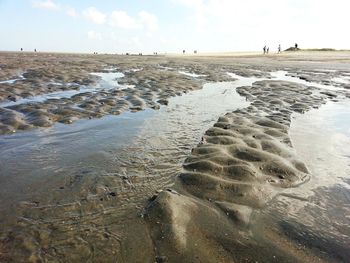 Surface level of wet sand on beach against sky