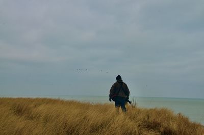 Rear view of man on beach against sky