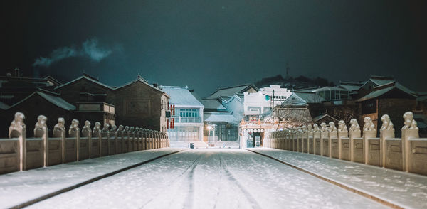 Street amidst buildings against sky during winter at night