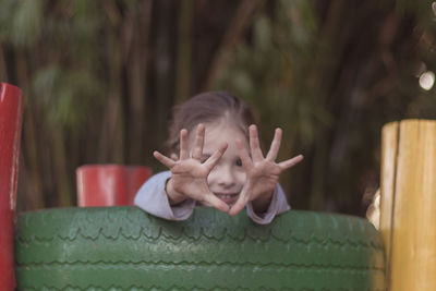 Portrait of girl showing hands on green tire