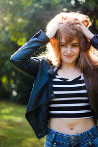 Woman with hand in hair standing at park