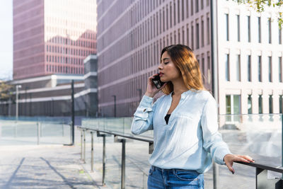Woman talking on phone while standing outdoors