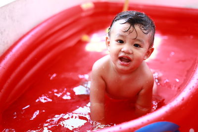 Portrait of shirtless baby boy in inflatable pool