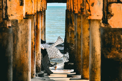 Low section of woman running below pier at beach