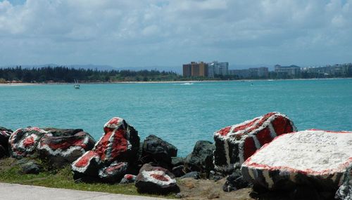 Painted rocks by sea against sky