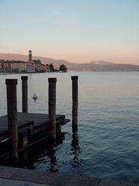 Wooden posts in sea against sky during sunset