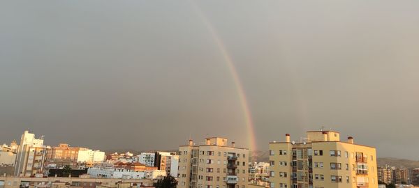 Low angle view of rainbow over buildings in city
