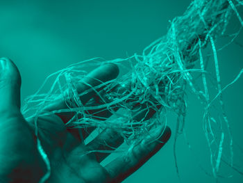 Close-up of human hand holding intertwined plastic fiber