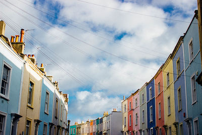 Low angle view of multi colored buildings against cloudy sky