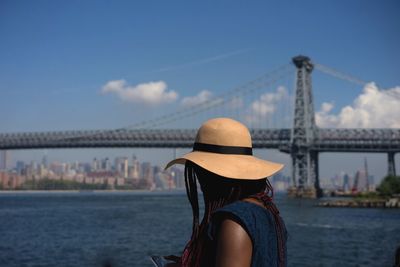 Woman looking at williamsburg bridge over east river against sky