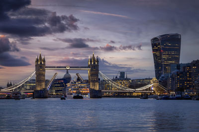 Illuminated bridge over river against sky at night