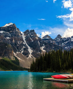 Scenic view of lake with canoes and mountains in background