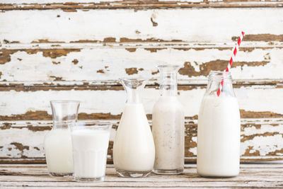 Milk in bottles and glass on table