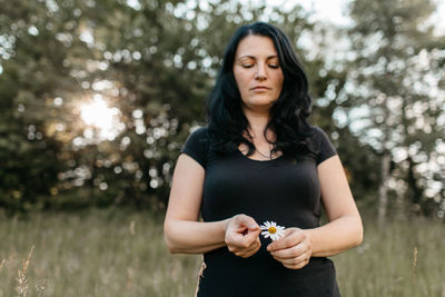 Beautiful woman with daisy flower standing on grass