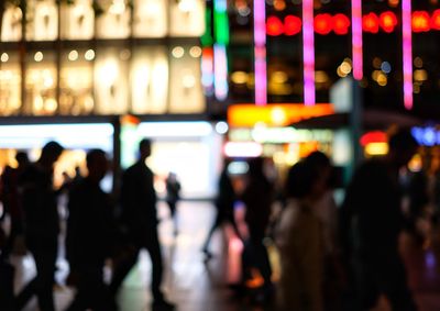 Defocused image of people on illuminated street at night