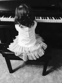 Rear view of girl playing piano
