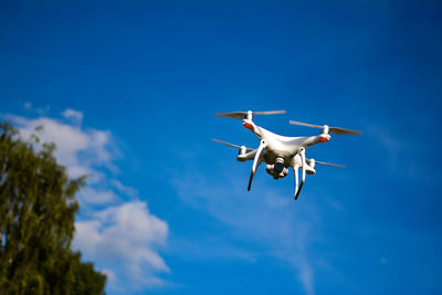 Low angle view of helicopter flying against blue sky