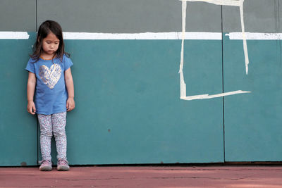 Full length of girl standing against wall