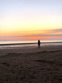 Silhouette people on beach against sky during sunset