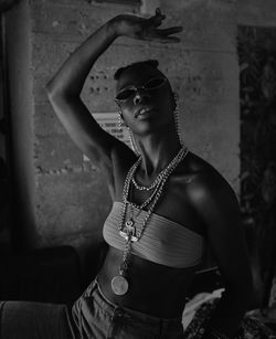 Portrait of young woman wearing sunglasses against wall