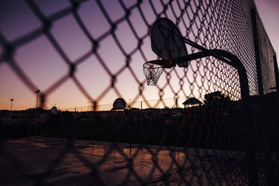 Silhouette fence against sky during sunset