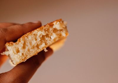 Close-up of hand holding burger against white background