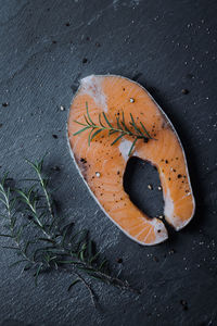 Fresh salmon slice with rosemary on dark stone background