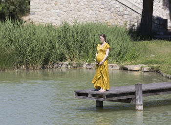 Pregnant woman standing on pier at lake