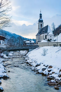 Snow covered buildings by mountain against sky