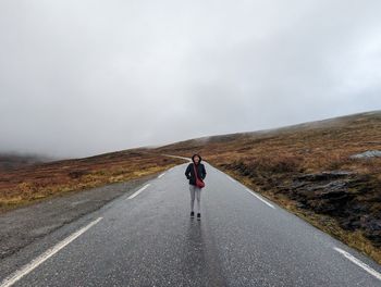 Rear view of man walking on road against sky