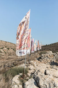 Low angle view of flag on rock against clear sky