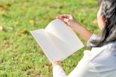 Midsection of woman holding umbrella on field