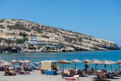 People on beach against clear blue sky