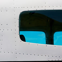 Close-up of airplane window against blue sky