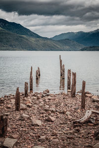 Wooden posts in lake against mountains