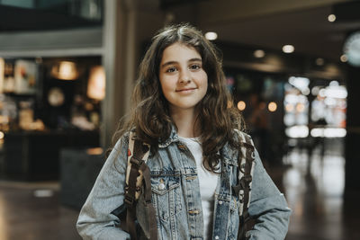 Portrait of smiling girl with long hair wearing denim jacket at station
