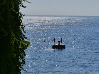 People on sea against clear sky