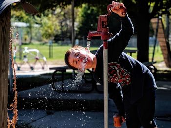 Boy drinking water from tap in park