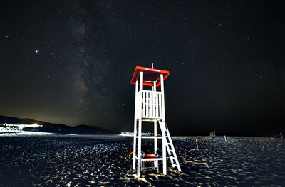 Lifeguard hut on beach against sky at night