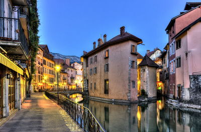 Canal amidst buildings against blue sky at dusk