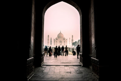 People and taj mahal seen through arch against sky