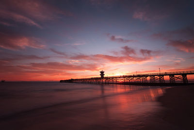 Silhouette of bridge over sea during sunset