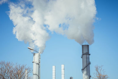 Low angle view of smoke emitting from chimney against sky