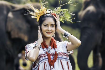 Portrait of young woman standing against plants