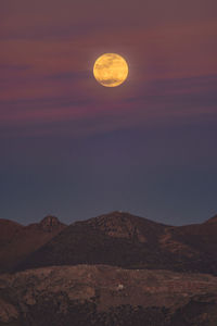 Scenic view of moon over mountains against sky at night