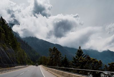 Road by trees against sky