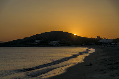 Scenic view of beach against clear sky during sunset