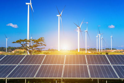 Wind turbines on field against sky