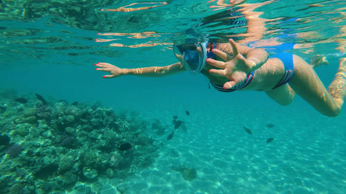 In the sea, a girl in a special snorkeling mask swims, examines fish, corrals, the beauty of the