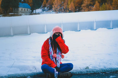 Woman sitting by snow covered field